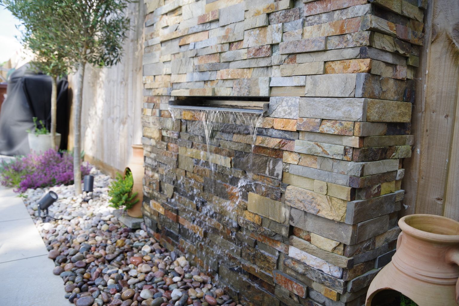 Studio Hummingbird | Project Ferring A waterfall feature with split face tile cladding and thyme growing underneath.