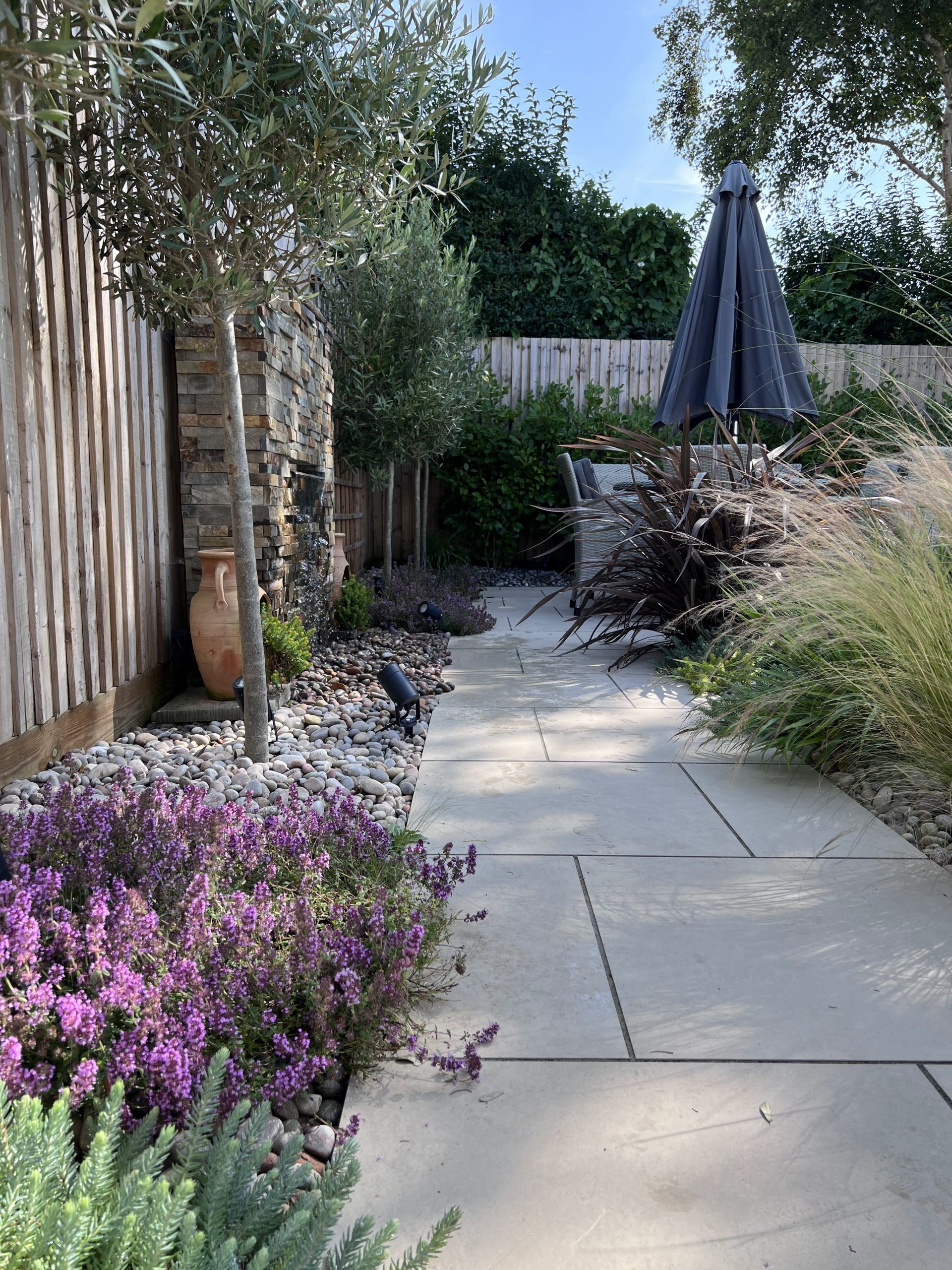 IMG_7112 A porcelain paved path next to a waterfall feature.