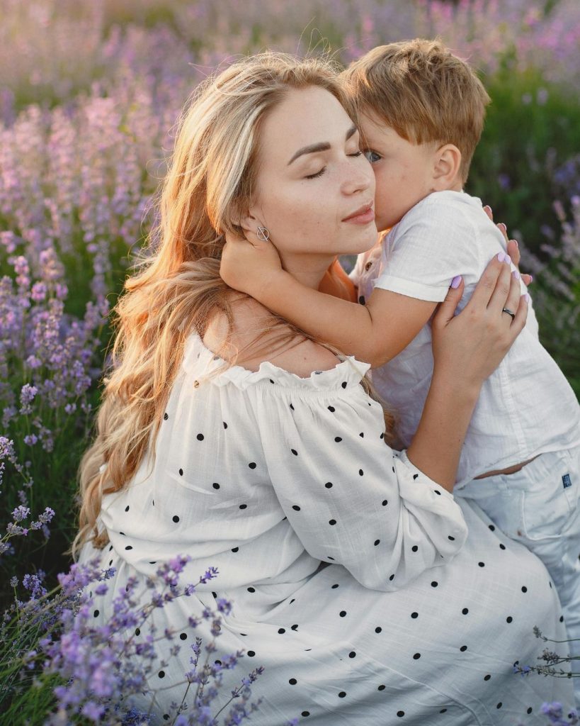 Mother holding her son in a field of lavender plants. A well-designed garden for neurodiverse wellbeing.