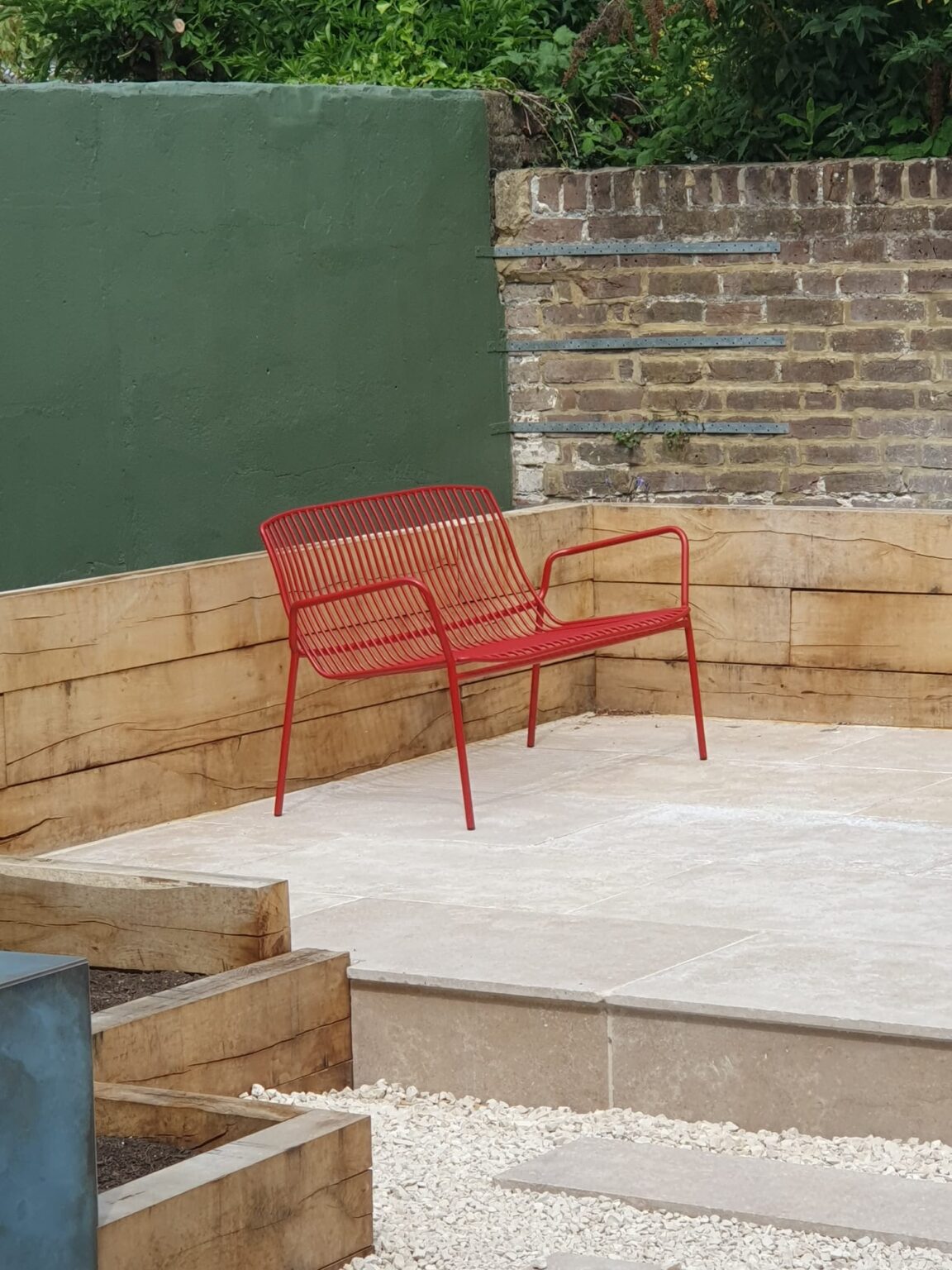 A red bench on a limestone patio.