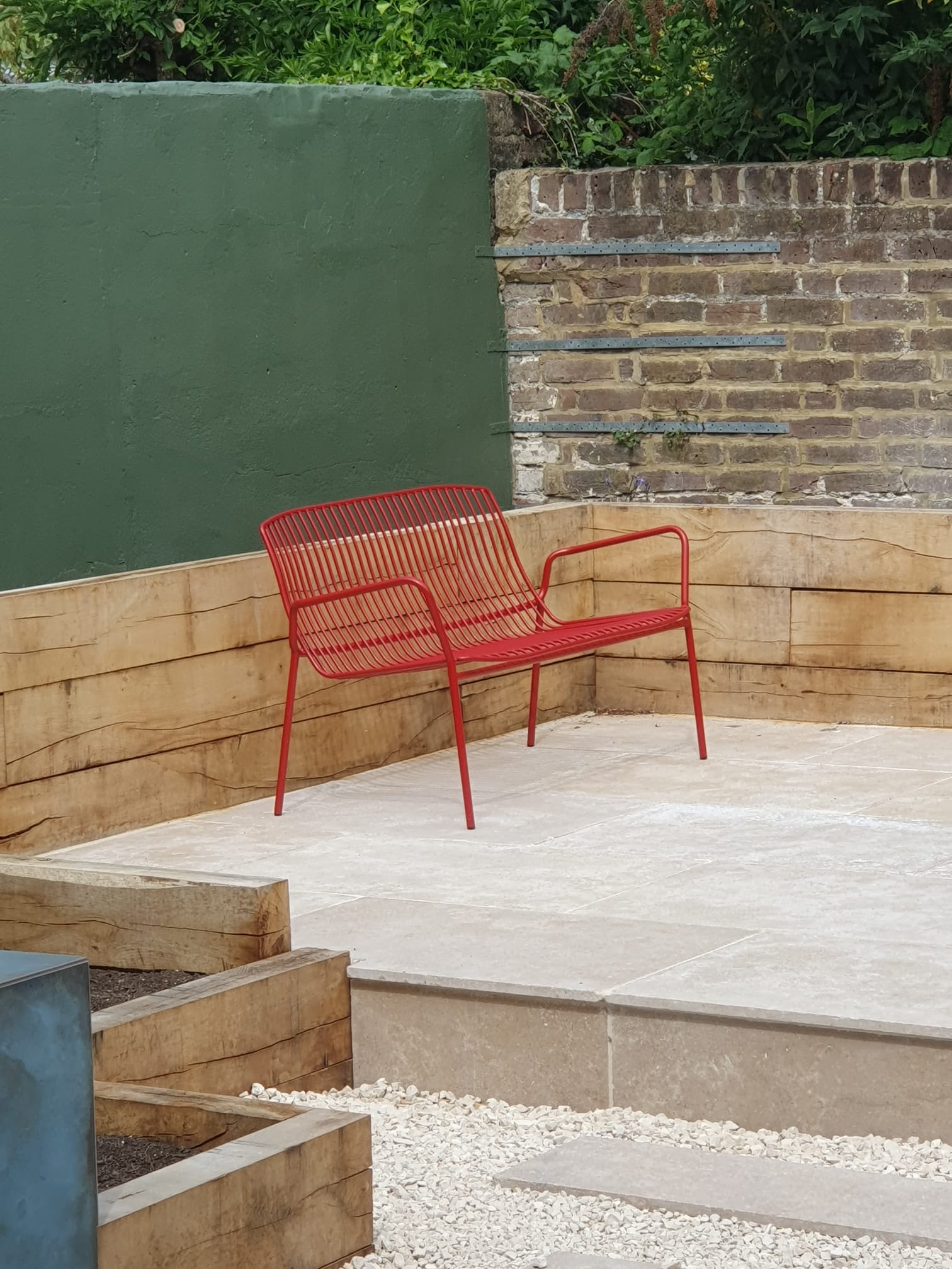 cea4aaf6-c42b-4385-ac83-2bc580478b8a A red bench on a limestone patio.