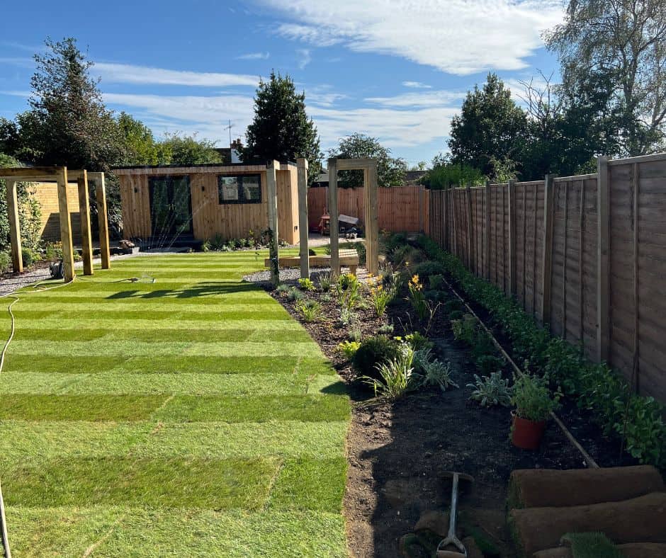 Completed garden design in Sussex with new lawn and planting beds as well as wooden bench and structures for climbing plants.